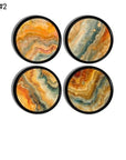 Set of four handmade drawer pulls with intricate fluid art designs. Each knob showcases swirling waves blending warm amber orange, teal blue, and beige gold hues on a round, black base handle. Uniquely stylish and artistic replacement hardware for furniture and cabinets.