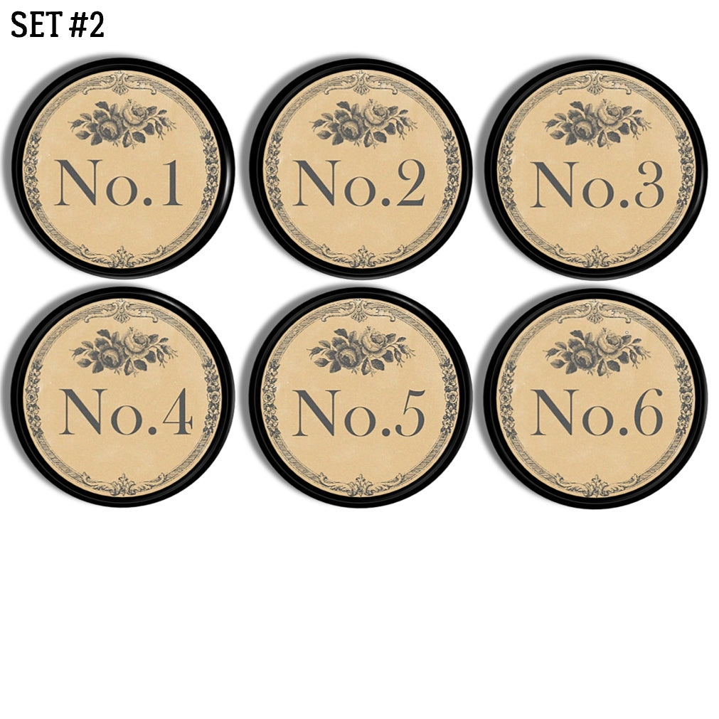 Set of 6 handmade black drawer pulls. The face of each knob is decorated with numbers 1-6 in a charcoal gray vintage Victorian font. The outer edge has small gray floral scroll detailing with a simple gray ornamental rose just above the number.