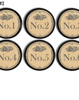 Set of 6 handmade black drawer pulls. The face of each knob is decorated with numbers 1-6 in a charcoal gray vintage Victorian font. The outer edge has small gray floral scroll detailing with a simple gray ornamental rose just above the number.