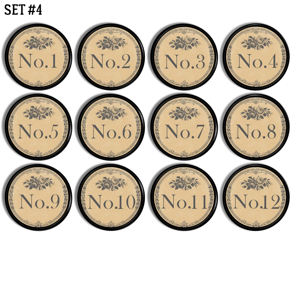 12 handmade round drawer pulls decorated in antique door plate style numbers with a French Quarters feel. Design colors are gray and background is beige. Knob base is black. 