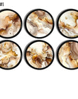 Six handcrafted abstract marble cabinet knobs with brown, beige, white, and gold fluid swirl patterns on a black base, designed for neutral, modern rustic, organic modern, transitional, and contemporary décor.