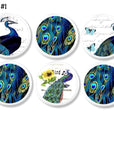 6 Decorative white knobs with bright blue peacock on white background with butterfly and sunflower accents.