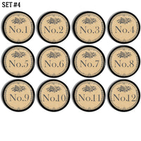 12 handmade round drawer pulls decorated in antique door plate style numbers with a French Quarters feel. Design colors are gray and background is beige. Knob base is black. 